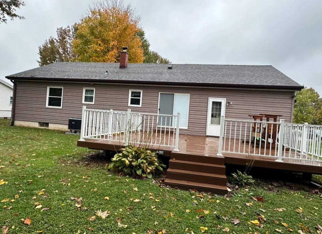 Gray asphalt shingle roof on single-story home with brick chimney and white deck railings