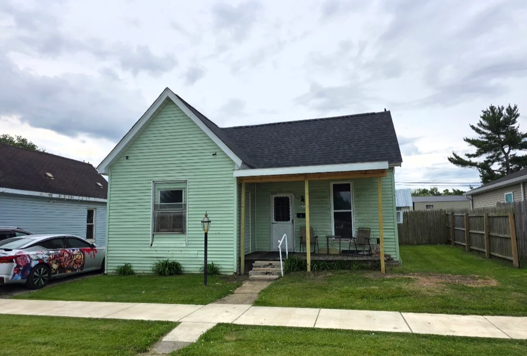 Dark gray asphalt shingle roof on mint green house with front porch