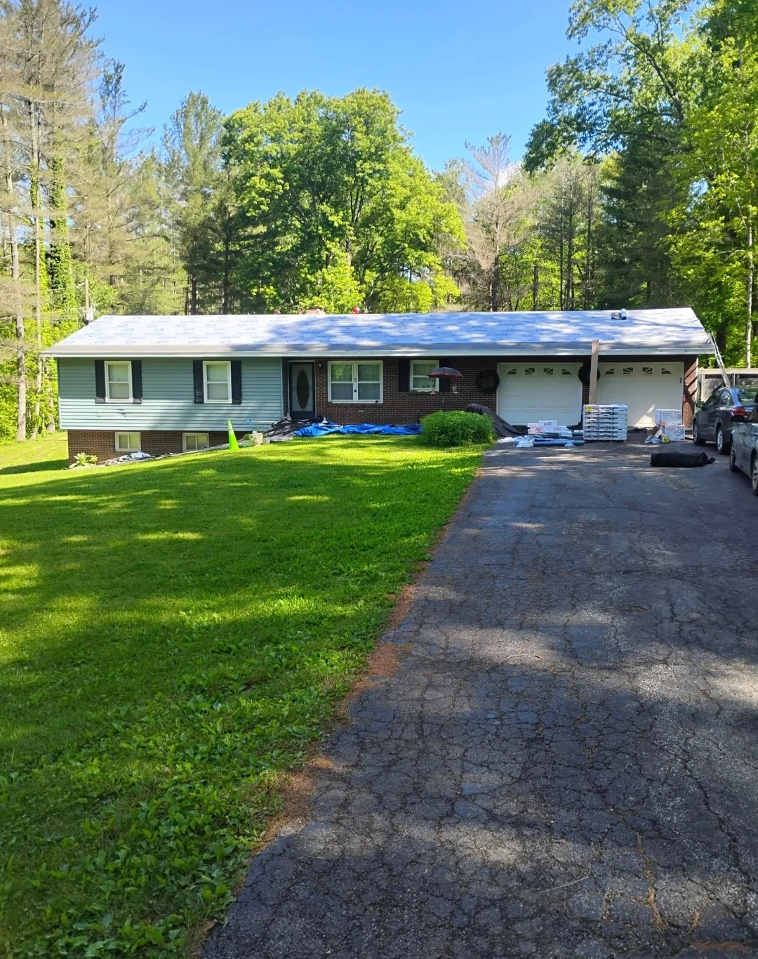 Brick home with new asphalt shingle roof installation, two-car garage, vinyl siding
