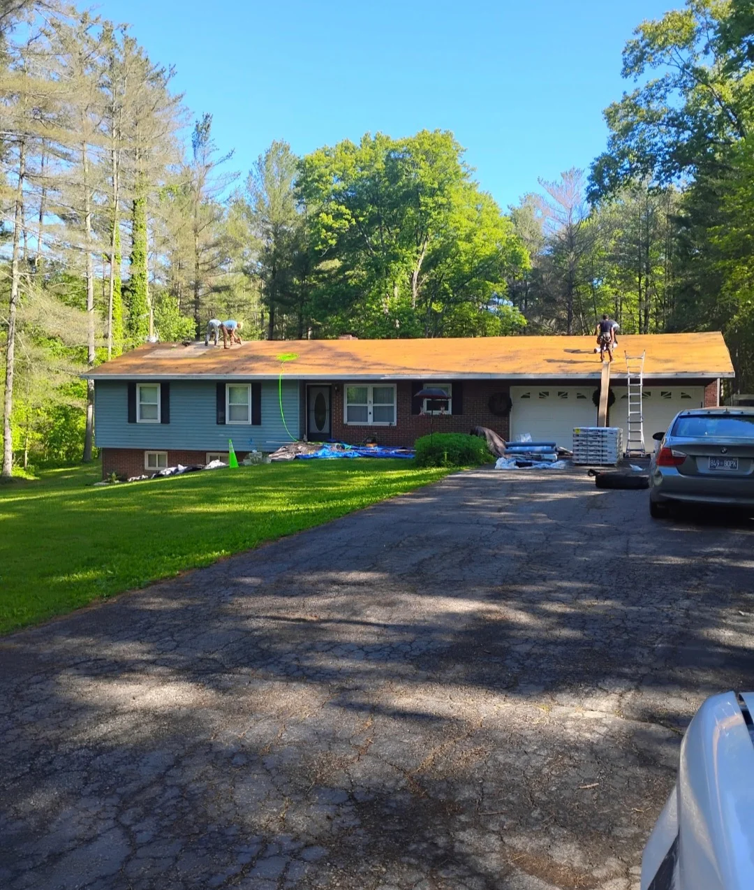 Brick ranch home with new orange-brown architectural shingles installed on roof during replacement project