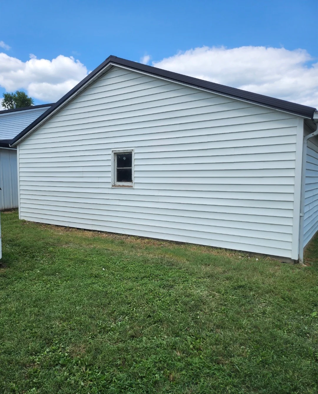 White vinyl horizontal siding with dark roof trim on residential garage structure