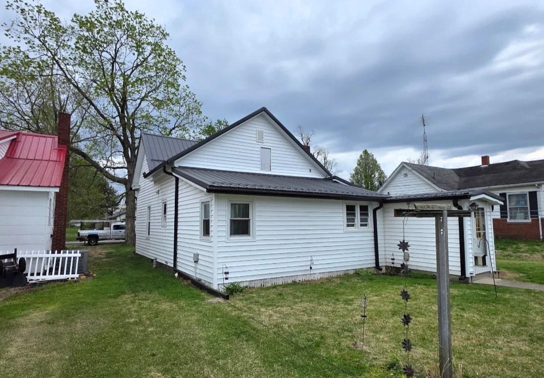 New asphalt shingle roof on white vinyl-sided residential home with black trim
