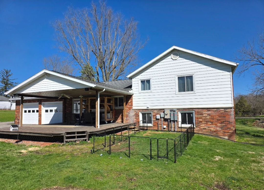 Split-level home with white vinyl siding, brick base, new roof, and composite deck with metal railings
