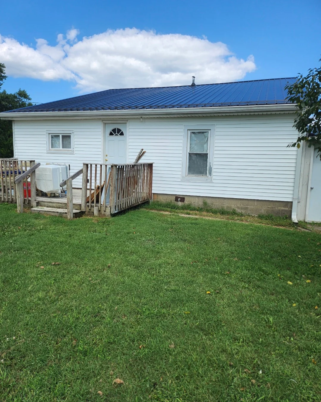 Dark blue standing seam metal roof installed on white vinyl-sided residential home
