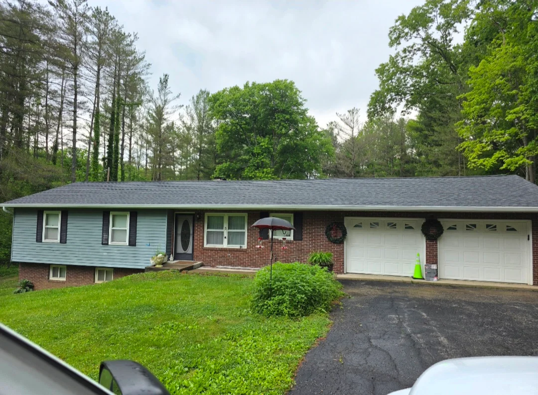 Slate gray asphalt shingle roof on brick and vinyl-sided split-level home with two-car garage