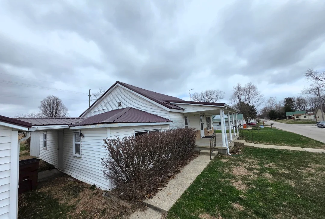 New dark asphalt shingle roof installed on residential home with white vinyl siding and covered porch