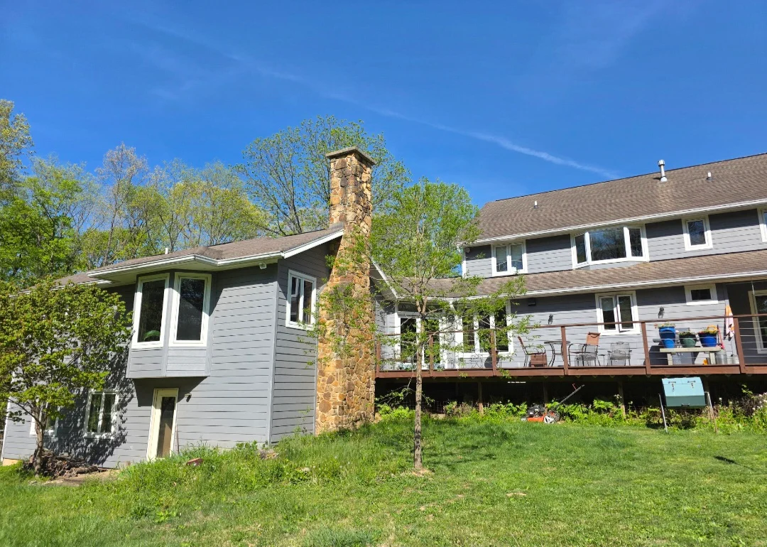 Gray asphalt shingle roof on multi-level home with stone chimney and white siding
