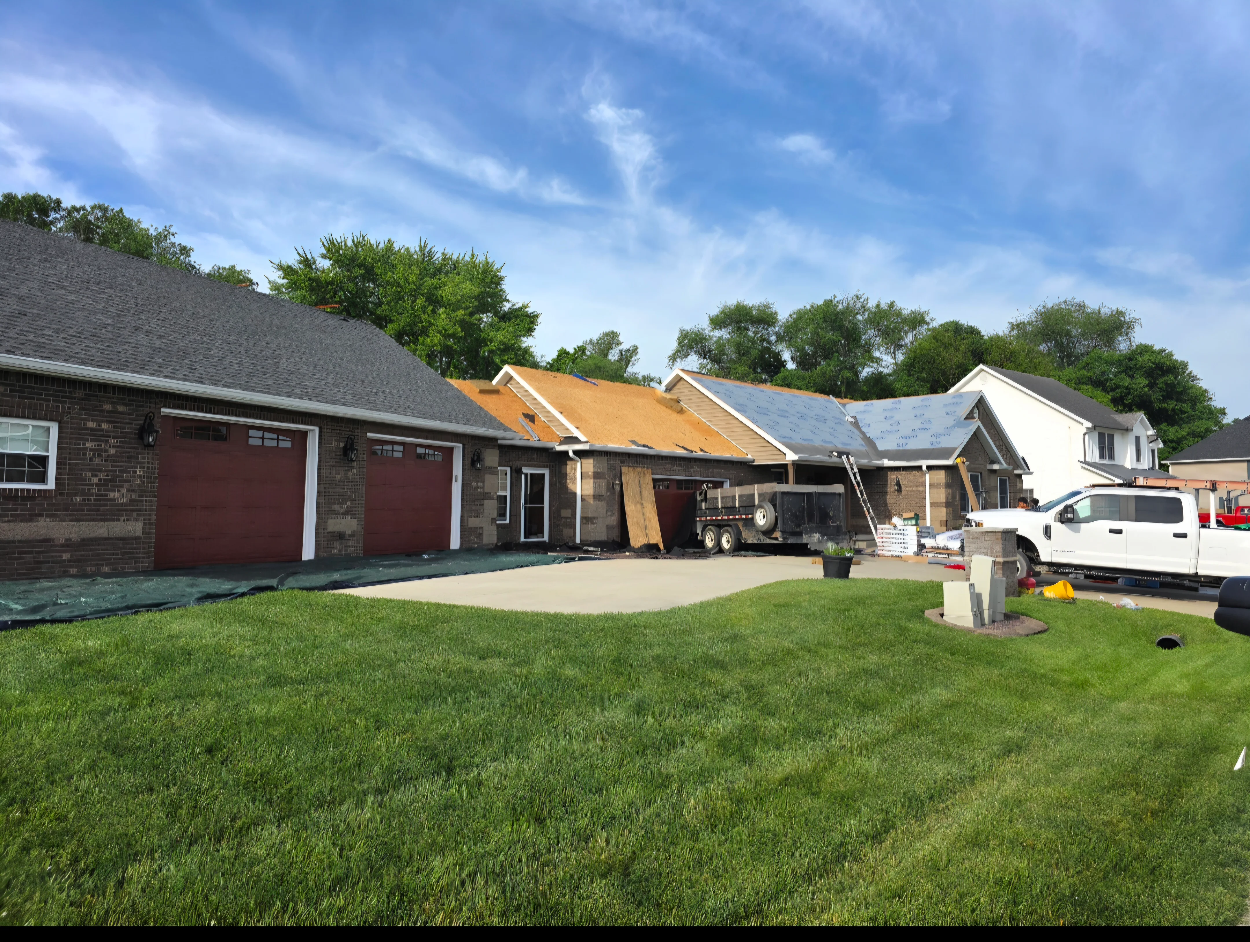 Multiple homes with new asphalt shingles, yellow underlayment, and blue weather barriers during active roofing installation
