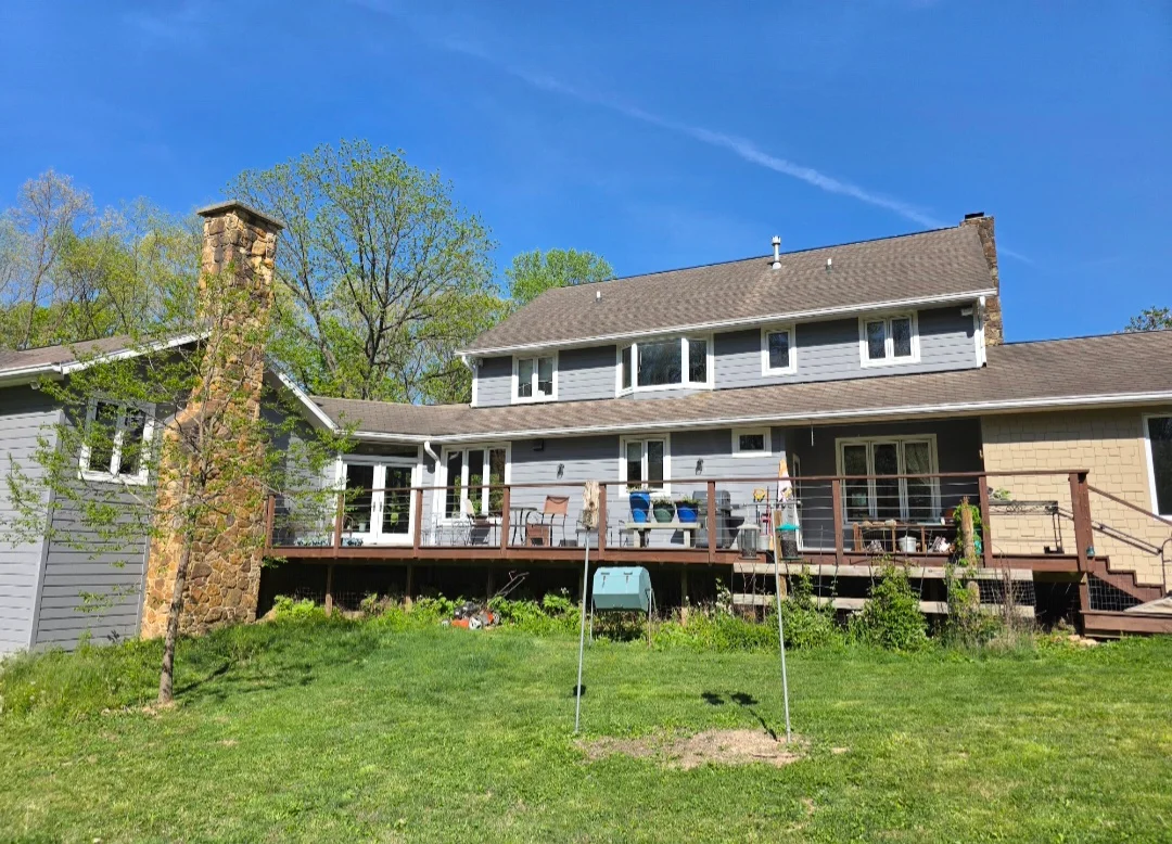 Two-story home with new dimensional asphalt shingle roof, white and tan siding, and wood deck