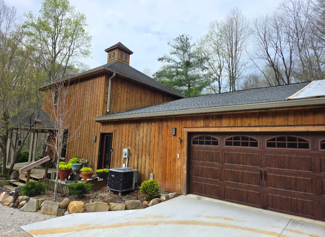 Charcoal gray architectural shingle roof on barn-style home with cupola and brown garage doors