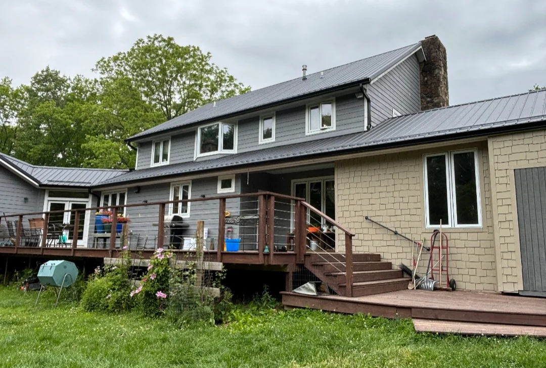 Standing seam metal roof installation on residential home with brick and siding exterior